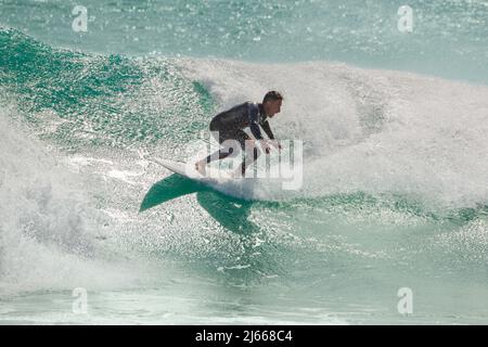 Surfista a cavallo di una cresta d'onda su una tavola da surf bianca nelle Isole Canarie. Foto Stock