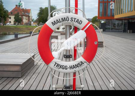 Una cintura di salvataggio Trygg-Hansa a Gamla staden, Fiskehamnsgatan, Malmo stad. Un rosso e bianco lifbuoy un simbolo per l'assicurazione Foto Stock