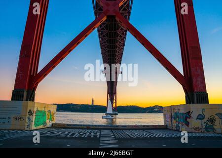 Lisbona, Portogallo - novembre 14 2022 - dettaglio del Ponte dell'aprile 25th (Ponte 25 de Abril) che attraversa il fiume Duoro con traversata in barca a vela Foto Stock