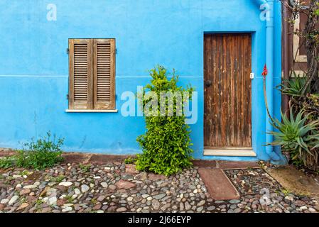 Porta e finestra in legno su parete blu, Bosa, Sardegna, Italia Foto Stock