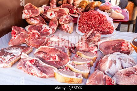 Carni fresche grezze tagliate pronte per la vendita nel mercato agricolo locale Foto Stock