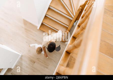 L'uomo bianco e suo figlio scendendo le scale di legno a casa Foto Stock