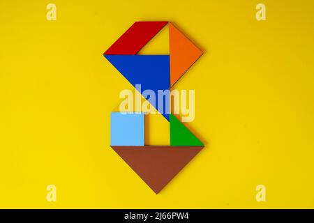 Colorato numero 8 fatto con tangram giocattolo, tangram colorato numero sette isolato su sfondo giallo, vista laterale del settimo numerico, idea di gioco per bambini Foto Stock