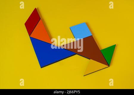 Colorato numero 4 fatto con tangram giocattolo, tangram colorato numero sette isolato su sfondo giallo, vista laterale del settimo numerico, idea di gioco per bambini Foto Stock