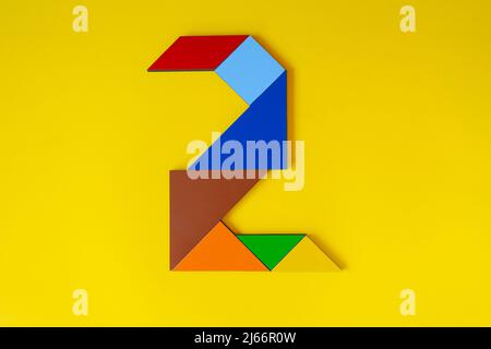 Colorato numero 2 fatto con tangram giocattolo, tangram colorato numero sette isolato su sfondo giallo, vista laterale del settimo numerico, idea di gioco per bambini Foto Stock