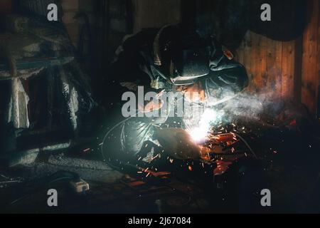 la saldatrice operatrice realizza un giunto di giunzione su un tubo mentre lavora in un'officina Foto Stock