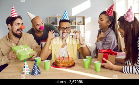 Sorridente ragazzo afroamericano soffiare candele sulla torta di compleanno Foto Stock