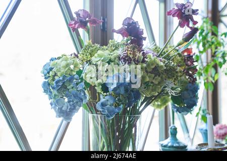 Bella hydrangea blu fiori in un vaso di vetro sullo sfondo del window.Beautiful bouquet di fiori in un vaso sul davanzale interno. Foto di alta qualità Foto Stock