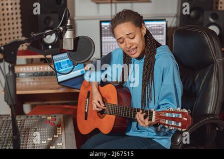 Affascinante nuova artista wave, chitarrista afro-americana, che registra la sua nuova canzone in studio di registrazione sonora Foto Stock