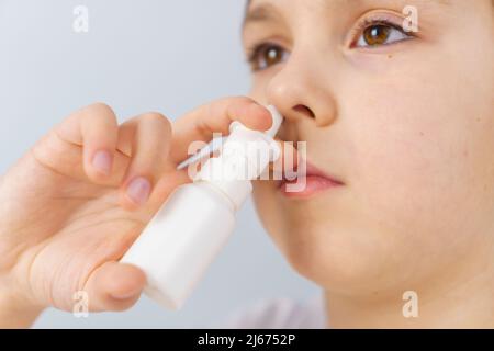 Bambina con naso che cola fa irrigazioni spray nasali per fermare la rinite allergica e sinusite Foto Stock