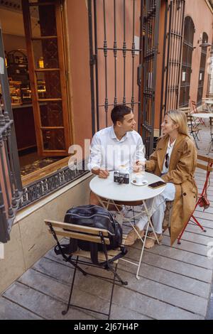 Giovane coppia seduta al tavolo di strada caffè e parlare Foto Stock