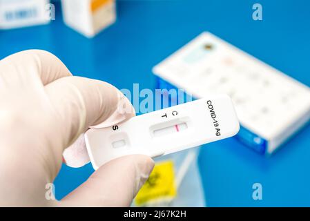 Mano con guanto che contiene una striscia di test dell'antigene rapido Covid-19 che mostra un risultato negativo. Foto Stock