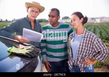 Coltivatori che discutono le carte vicino all'automobile sull'azienda agricola Foto Stock