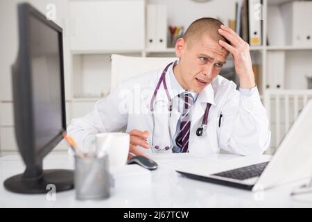 medico che utilizza un computer portatile che lavora alla scrivania Foto Stock