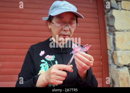 YICHANG, CINA - 27 APRILE 2022 - gli artisti folkloristici mostrano le loro capacità di patrimonio culturale immateriale, come il taglio della carta e la figurina di pasta, al Fuf Foto Stock