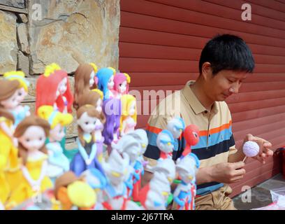 YICHANG, CINA - 27 APRILE 2022 - gli artisti folkloristici mostrano le loro capacità di patrimonio culturale immateriale, come il taglio della carta e la figurina di pasta, al Fuf Foto Stock