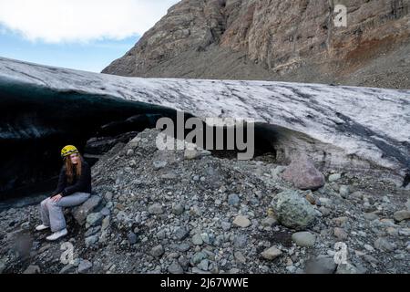 Una ragazza adolescente siede fuori da un ghiacciaio del ghiacciaio Brei amerkurjškull. Parco Nazionale di Vatnajškull lungo la costa meridionale dell'Islanda. Foto Stock