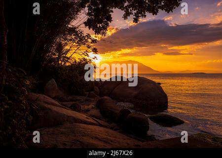 Tramonto incredibile sulla spiaggia con grandi pietre e mare tranquillo a Florianopolis, Brasile Foto Stock