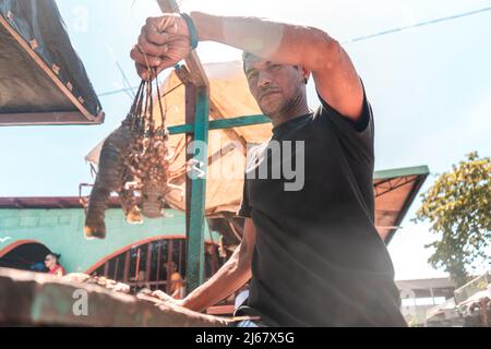 Il pescatore Latino mostra un'aragosta appena pescata in un mercato. Tipo documentario foto di persone reali Foto Stock