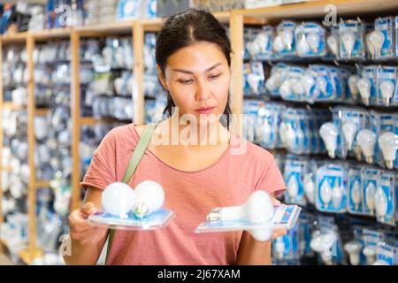 La donna ha scelto la lampada a risparmio energetico presso il negozio di hardware Foto Stock