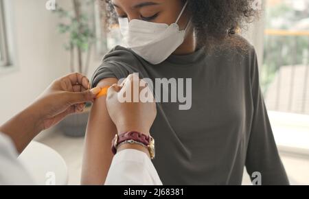 Il medico afroamericano sta applicando il gesso alla spalla di un bambino dopo essere stato vaccinato. Maniche di apertura per vaccinare contro l'influenza o l'epidemia in guarire Foto Stock