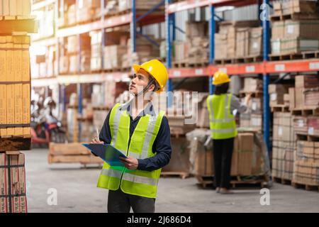 Addetto al magazzino che controlla le confezioni su scaffale in un grande negozio Foto Stock