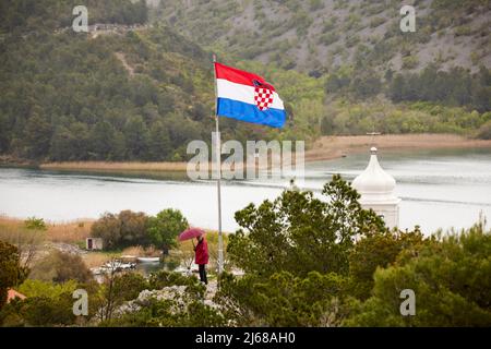 Skradin una piccola città nella contea di Šibenik-Knin della Croazia, il fiume Krka e il campanile della Chiesa di Mala Gospa e la bandiera nazionale dal castl Foto Stock
