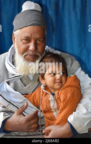 INDIA, UTTTAR PRADESH, VILLAGGIO DI BARABANKI, dicembre 2021, Ritratto un nonno felice e nipote. Nipote sorridendo e seduto sul grandfat Foto Stock