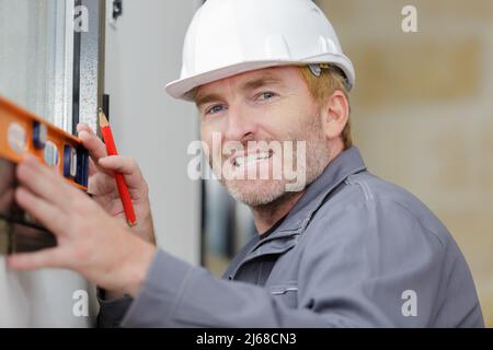 un uomo commerciale sorridente che usa il livello dello spirito Foto Stock