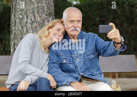 padre in pensione e figlia di mezza età prendendo selfie all'aperto Foto Stock