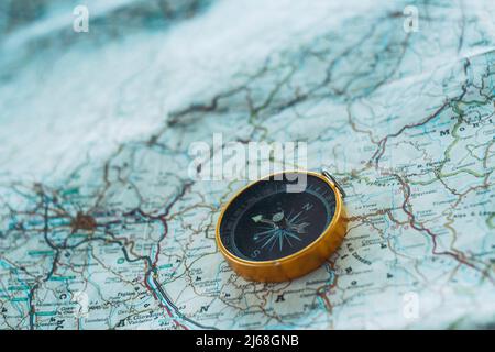 Primo piano della bussola sulla guida cartacea. Concetto di stile di vita di viaggio e avventura. Pianificare un viaggio su strada per una nuova scoperta. Viaggiatori e prossimo viaggio des Foto Stock