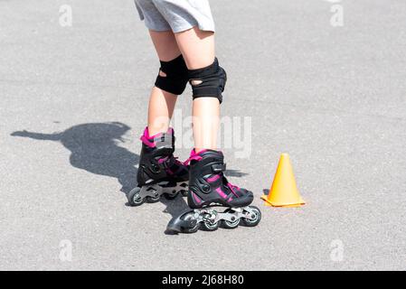 Bambina facendo andare in rollerblade in strada Foto Stock