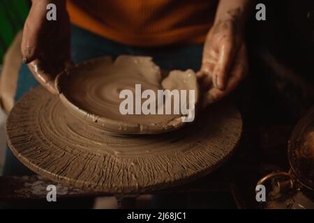 donna fa piatto di argilla in ceramica laboratorio, sfondo bello, atmosfera autentica, stile di vita. lampada gialla. tenerezza, amore, naturalezza, eco Foto Stock