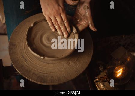 la donna fa piatto di argilla in laboratorio di ceramica, sfondo bello, atmosfera autentica, stile di vita. lampada gialla Foto Stock