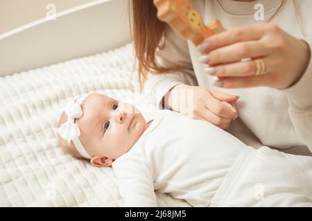 la madre gioca con il neonato, la bambina esplora il mondo, guarda il giocattolo. Sviluppo precoce, studio. Giraffa di legno Foto Stock