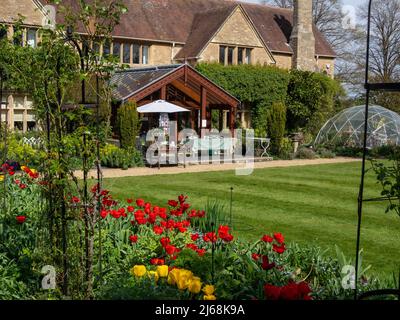 Vista della primavera attraverso il prato alla Manor House, letto di fiori in primo piano, Kathy Brown's Garden, Stevington, Bedfordshire, Regno Unito Foto Stock