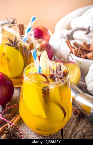 Boozy Pumpkin Party Punch, sangria di ringraziamento con succo di zucca, mela, pera e spezie, fondo in legno accogliente con maglione caldo e ingredienti c Foto Stock