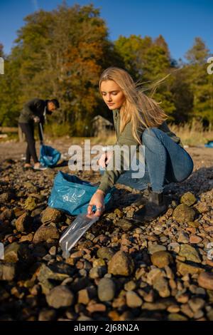 Seria giovane donna in ambiente conservazione squadra raccogliere plastica in spiaggia Foto Stock