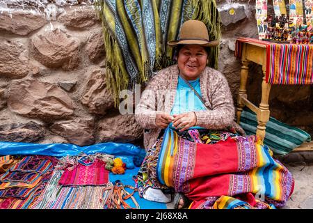 Una donna indigena mostra i suoi souvenir fatti a mano / artigianato al mercato Domenica nella città di Pisac, la Valle Sacra, provincia di Calca, Perù. Foto Stock