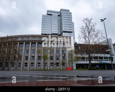 Alto edificio dell'assicurazione pensioni tedesca. Architettura con una moderna facciata in alluminio del 1970s. Punto di riferimento futuristico e cielo nuvoloso. Foto Stock