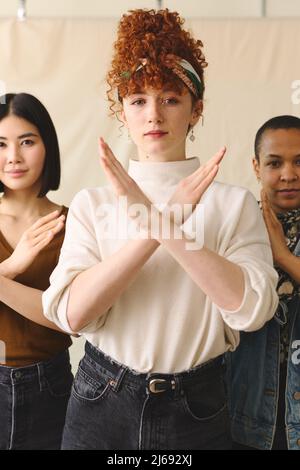 Giovane donna bianca gesturing Break the Bias a sostegno della Giornata Internazionale della Donna con amici multietnici femminili Foto Stock