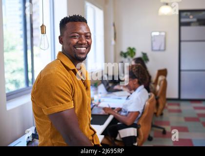 Un leader aziendale Black con il suo team nel loro ufficio open-plan creativo Foto Stock