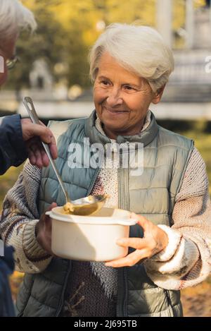 la donna anziana di medio colpo ottiene il cibo nel concetto di sostegno della gente anziana del parco. Foto di alta qualità Foto Stock