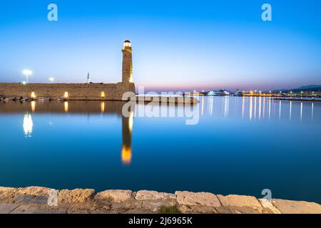 Vecchio faro riflesso nel mare calmo durante l'ora blu, Rethymno, isola di Creta, Isole Greche, Grecia, Europa Foto Stock