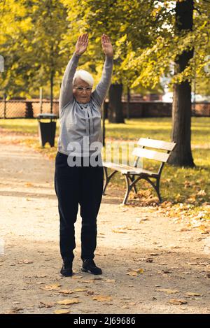 Donna caucasica anziana che fa ginnastica in parco pieno scatto copia spazio . Foto di alta qualità Foto Stock