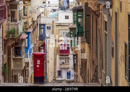 Tipica scena stradale di vicolo con case tradizionali, balconi colorati e casella postale rossa, Valletta, Malta, Europa Foto Stock