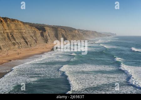 Spiaggia di Magoito con surfisti surf sulle onde del mare, vicino Sintra, Portogallo Foto Stock