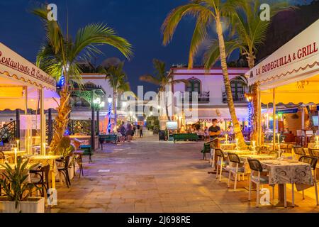 Vista di caffè e ristoranti a Puerto de Mogan e sfondo montuoso al tramonto, Puerto de Mogan, Gran Canaria, Isole Canarie, Spagna, Atlantico Foto Stock