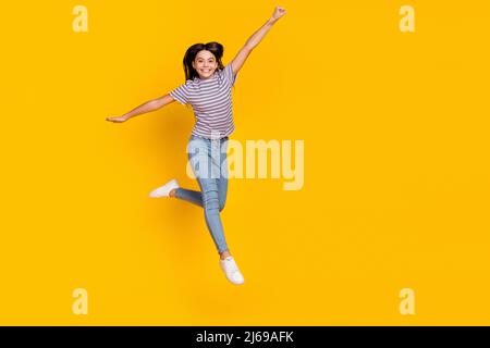 Foto del corpo pieno di giovane signora abbastanza eccitata hanno salto di divertimento su volare isolato su sfondo giallo di colore Foto Stock
