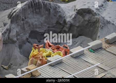 Cumulo di sabbia M e sacchi di cemento usati riempiti di sabbia e mattoni di calcestruzzo su un'area di costruzione Foto Stock